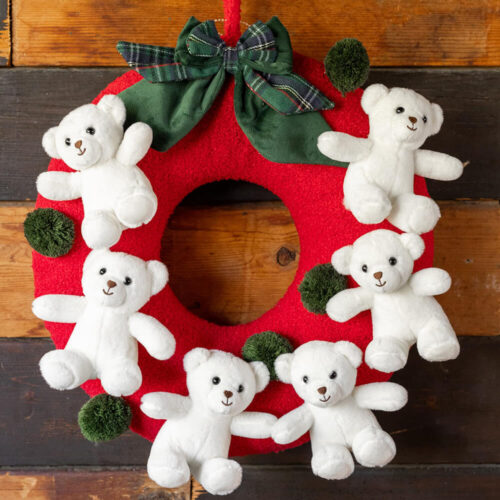Ghirlanda rossa decorativa con sei orsetti bianchi in peluche e fiocco scozzese verde, ideale come fuoriporta natalizio.