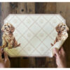 Mantel individual de vinilo con cachorro marrón claro sobre fondo beige decorado con huellas de patas.