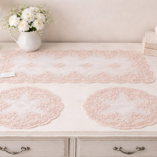 Tris di centrini Chez Moi in tessuto trasparente color polvere di cipria con ricami floreali in rilievo e bordo smerlato, composto da una striscia rettangolare e due centrini coordinati.