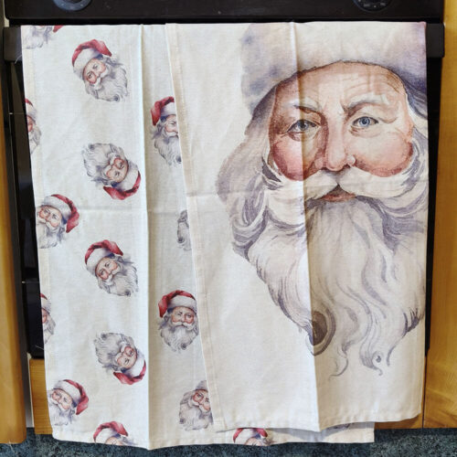 Lot de deux torchons de Noël en coton : l'un avec une impression répétée du visage du Père Noël, l'autre avec un portrait aquarelle en pied sur fond clair.