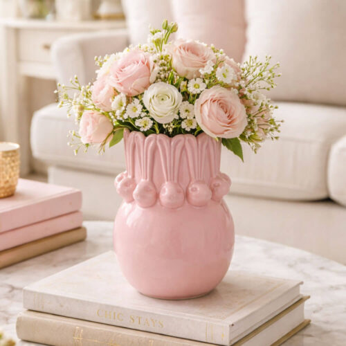 Vaso pasquale rosa in ceramica lucida con decori di conigli in rilievo e forma bombata.