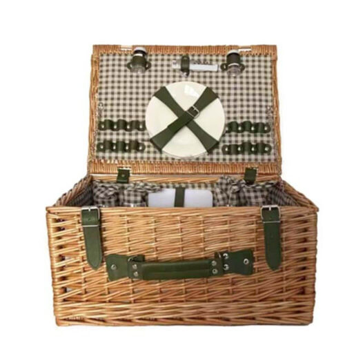 Panier pique-nique en rotin avec attaches en simili-cuir vert, intérieur à carreaux, complet avec assiettes et accessoires.