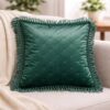 Cuscino quadrato in tessuto lucido color verde con trapuntatura a rombi e frange ai bordi.