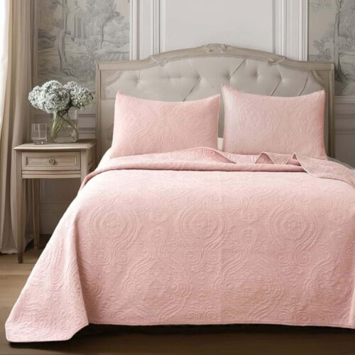 Couette double rose avec motif damassé gaufré, combinée à deux oreillers, sur un lit avec tête de lit rembourrée de style classique.