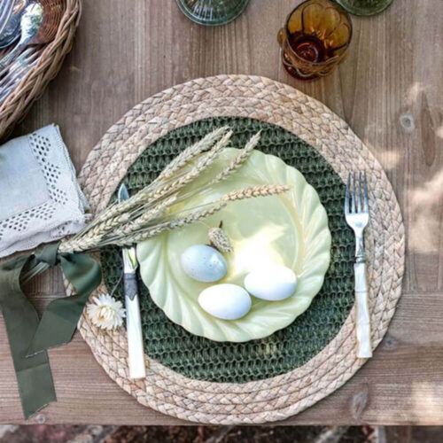 Sottopiatto rotondo in fibra naturale con bordo intrecciato beige e centro in rete verde oliva. Stile rustico e naturale.