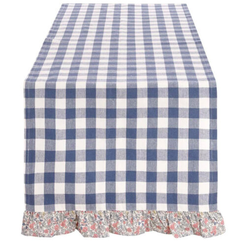 Runner Blanc Mariclò a quadri blu e bianchi con bordo floreale arricciato, su tavolo rustico con dolci e frutta.