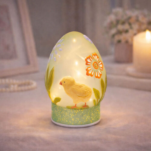 Decoro pasquale a forma di uovo verde in vetro con pulcino giallo, fiori decorativi e base glitterata con LED.