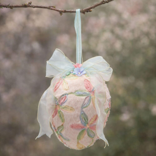Uovo decorativo rosa da appendere con fiocco in organza, fiori in tessuto e superficie effetto velluto.