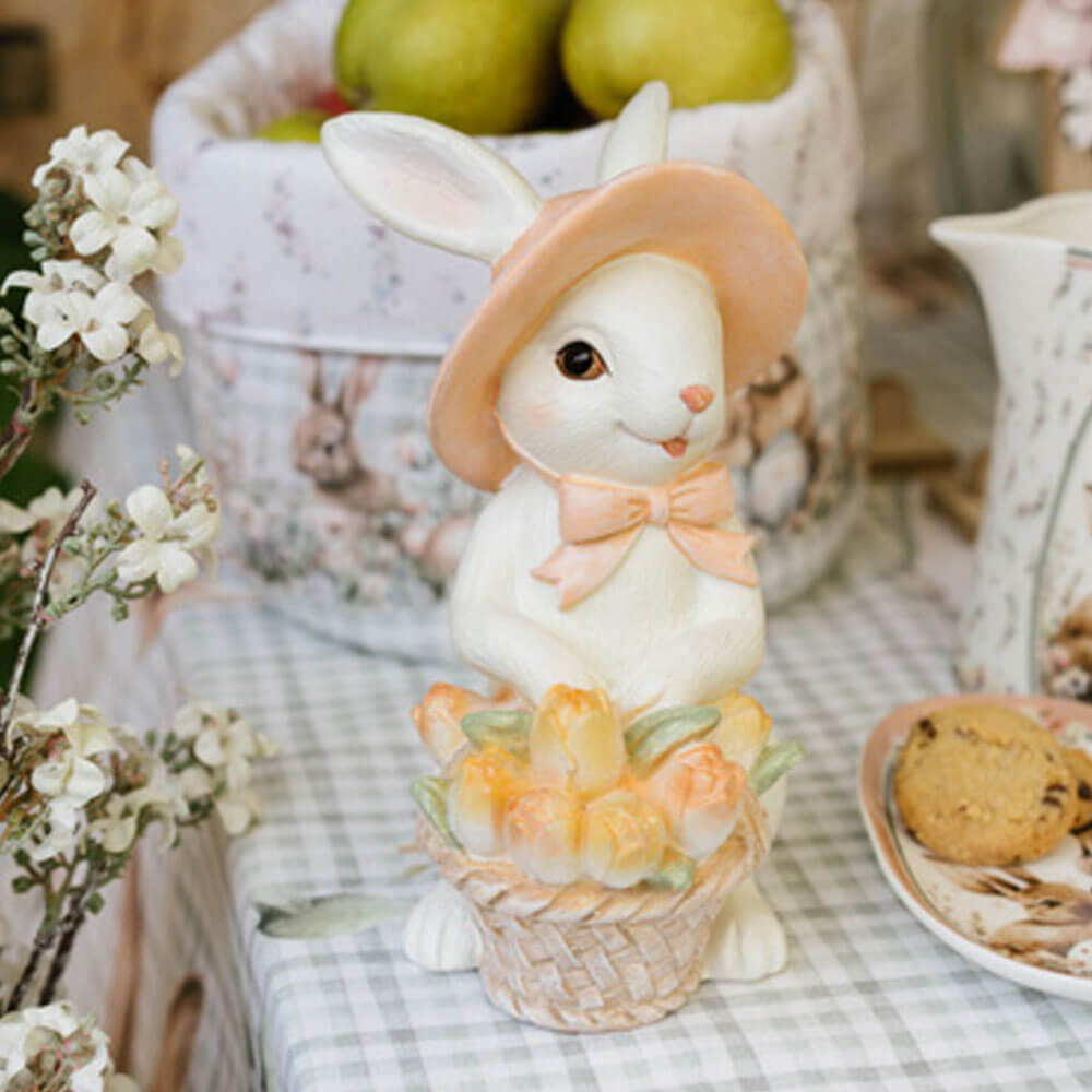 Coniglietta decorativa in resina con cappello rosa e cestino di fiori pastello.