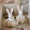 Coniglio PePen in resina su teiera o tazzina, decorazione pasquale assortita con dettagli floreali.