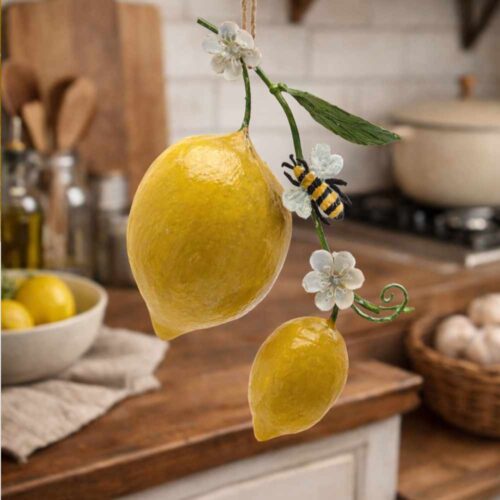 Adorno colgante de metal con dos limones amarillos, hojas verdes, flores blancas y una abejita, con cordón natural.