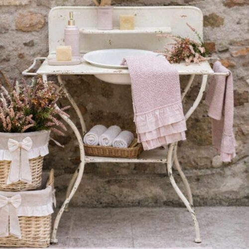 Meuble de salle de bain en métal ivoire avec vasque blanche amovible, dosseret avec petite étagère et poignées latérales.