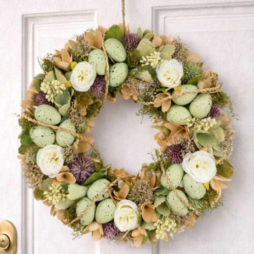 Ghirlanda pasquale Nuvole di Stoffa Pepen 33 cm con ovetti verde salvia maculati, fiori bianchi e dettagli lilla, da appendere.