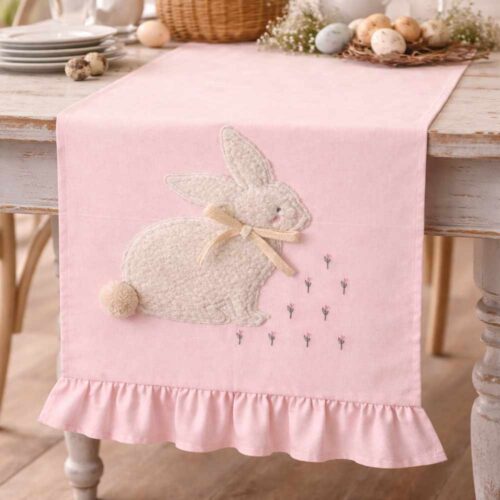 Chemin de table rose poudré avec appliqué de lapin bouclé, nœud beige, petites fleurs brodées et volant final.