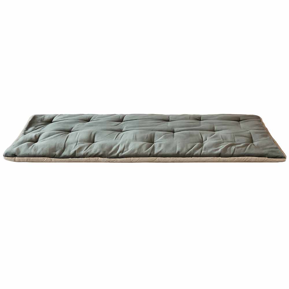 Dessus de canapé matelassé en velours vert sauge de Jaipur avec bordure beige, placé sur le canapé avec housse florale assortie.
