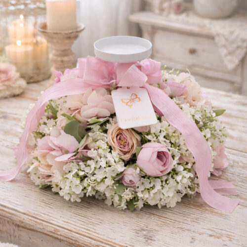 Candelabro Fiori di Lena con ortensia rosa e nebbiolina, fiocco rosa e piattino portacandela, centrotavola shabby chic su tavolo in legno.
