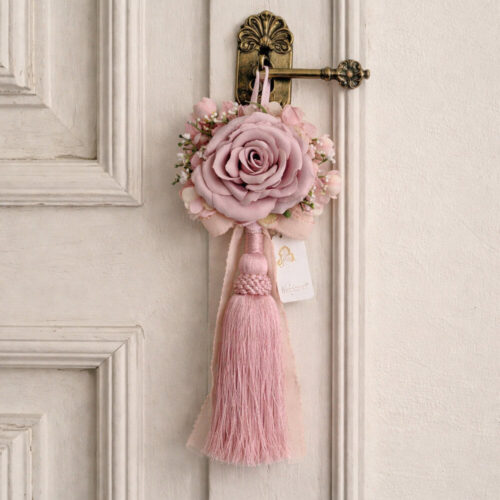 Borla decorativa rosa con toque real rosa, cinta y apliques florales, fleco largo en rosa.