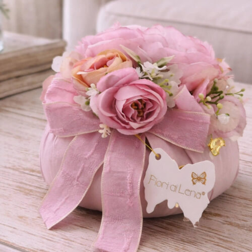 Pouf floreale Fiori di Lena con peonia cipria-malva, ortensia e due farfalle decorative, su tavolo in legno in stile shabby chic.