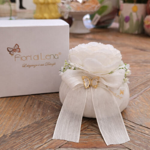 Pouf bianco Fiori di Lena con ranuncolo e farfalla applicata, fiocco avorio e scatola regalo, ideale come bomboniera shabby chic su tavolo in legno.