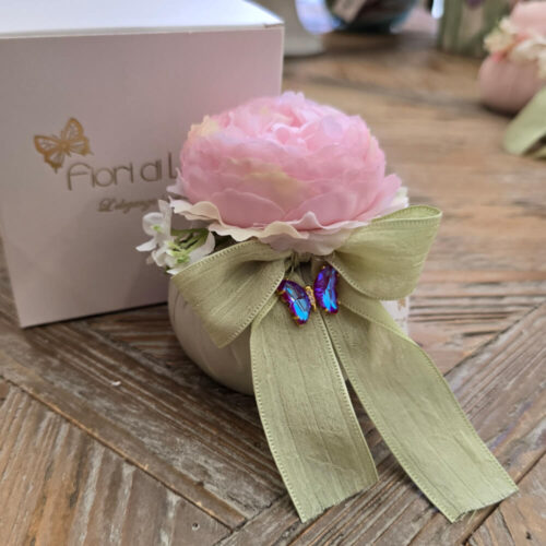 Pouf verde Fiori di Lena con ranuncolo rosa e farfalla applicata, fiocco verde e scatola regalo, su tavolo in legno stile shabby chic.