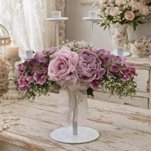 Candelabro de 4 llamas Fiori di Lena con rosas empolvadas y flores malva, lazo marfil y adornos de niebla, sobre una mesa de madera Shabby Chic.