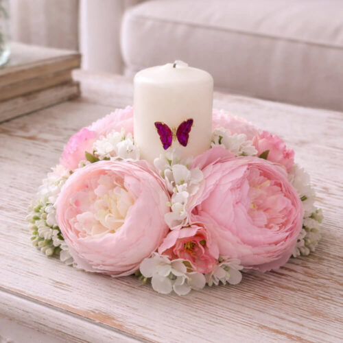 Corona Fiori di Lena con 4 ranuncoli rosa mix e candela avorio con farfalla applicata, composizione shabby chic profumata su superficie in legno.