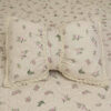 Cuscino decorativo Fiocco Fiore di Primavera L'Atelier 17 a forma di farfalla in poliestere avorio a righe con stampa floreale rosa e bordo in pizzo all'uncinetto, posato su trapuntino coordinato.