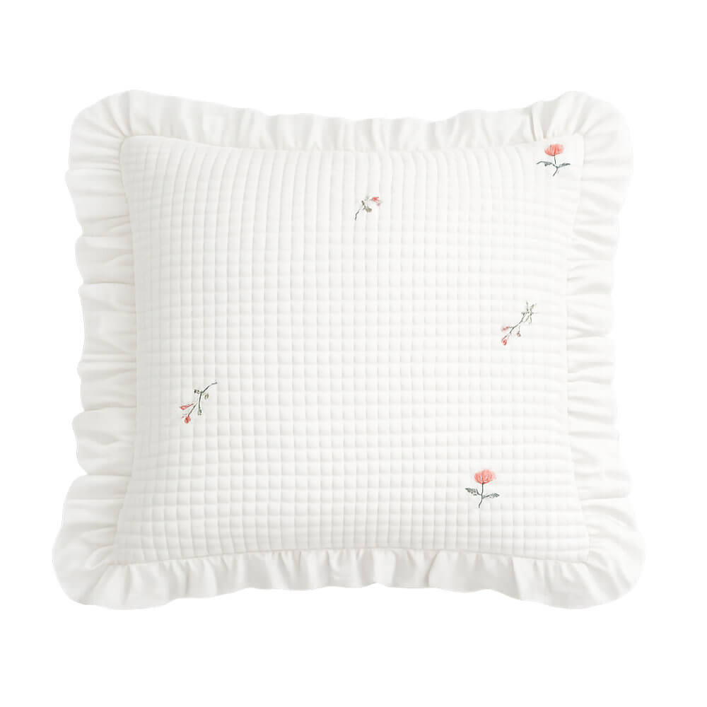 Coussin carré blanc avec une délicate broderie florale et une bordure à volants.