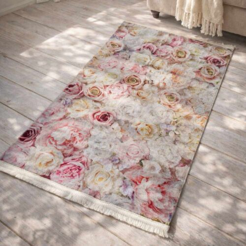 Tappeto velour L’Atelier 17 con fantasia di rose e fiori rosa e crema su fondo chiaro con frange decorative.