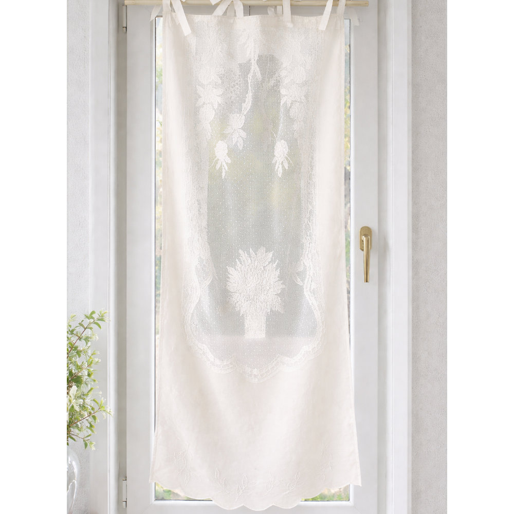Tendina Provenzale Margareth Avorio L'Atelier 17 in cotone avorio con ricami floreali tridimensionali su pizzo puntinato, medaglione centrale a vaso fiorito e bordo a festoni sagomati, fissaggio a laccetti in cotone, installata su finestra.