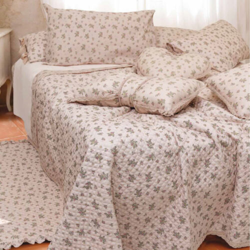 Trapuntino matrimoniale Cuor di Magnolia L'Atelier 17 in poliestere rosa cipria con stampa floreale di campo multicolore, trapuntatura a rombi e bordo in pizzo all'uncinetto, con due federe coordinate su letto shabby chic.