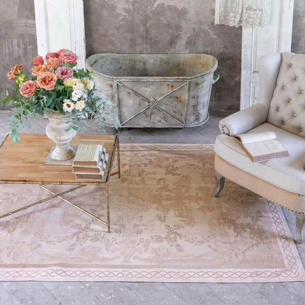 Tappeto rettangolare Blanc Mariclò collezione Sussurro in colore rosa cipria, con decorazioni floreali e arabeschi vintage su fondo chiaro e bordo intrecciato decorativo.