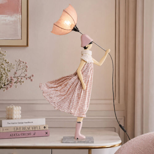 Lampada artigianale SKITSO Little Girl Lefkippi alta 85 cm con paralume rosa, abito rosa cipria fantasia geometrica, dettagli in maglia avorio e base decorata.