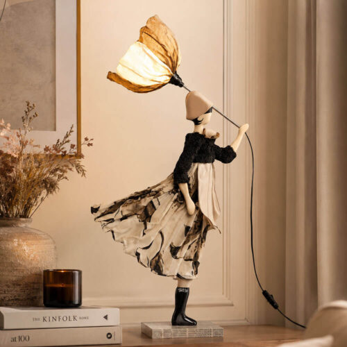 Lampada artigianale SKITSO Little Girl Minthi alta 85 cm con paralume a stampa floreale, abito nei toni avorio e sabbia, coprispalle nero e dettagli realizzati a mano.
