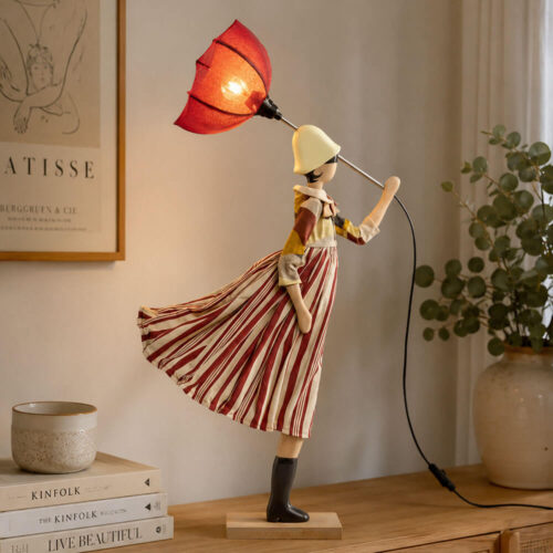 Lampada artigianale SKITSO Little Girl Roio in legno di faggio con abito a righe bordeaux e paralume bordeaux, figura femminile ispirata al vento, altezza 85 cm.