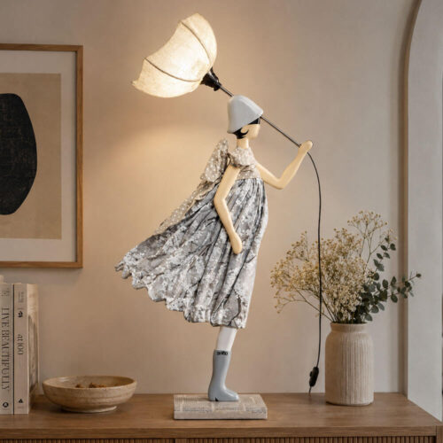 Lampada artigianale SKITSO Little Girl Ying alta 85 cm con paralume bianco, abito floreale grigio e fiocco beige a pois, realizzata a mano in Grecia.