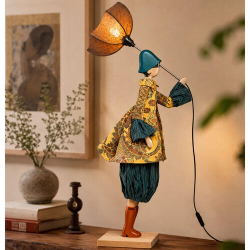 Lampada artigianale SKITSO Little Girl Ludovica alta 85 cm con paralume marrone, base in legno di faggio, cappotto decorato nei toni ocra e petrolio e dettagli tessili artigianali.