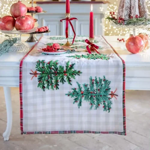 Runner da tavola Blanc Mariclò Magia di Abeti con ricami di rami di abete e bacche rosse su tessuto beige a quadri, rifinito con bordo tartan rosso, misura 45x150 cm.