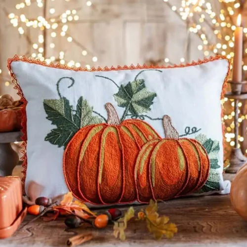 Cuscino Blanc Mariclò in cotone bianco con zucche arancio ricamate, foglie verdi e bordo rosso decorativo.