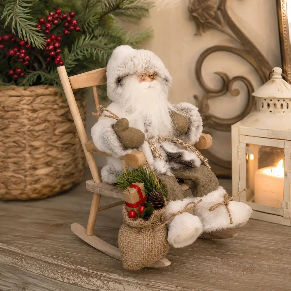 Babbo Natale decorativo vestito di bianco seduto su sedia a dondolo in legno, con sacco in juta e decorazioni natalizie, alto 30 cm.