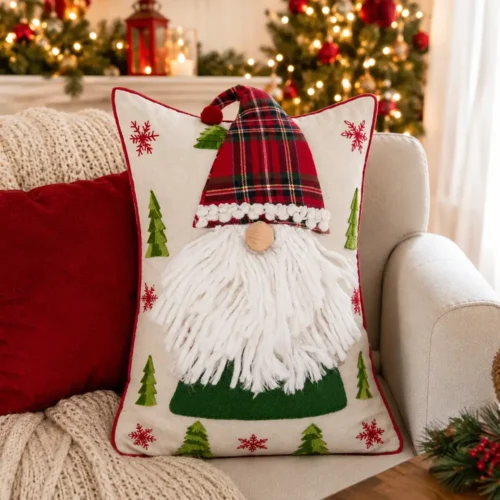 Cuscino Blanc Mariclò con gnomo, cappello tartan rosso e verde, barba bianca, abeti applicati e fiocchi di neve rossi.