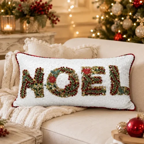 Cuscino natalizio Blanc Mariclò bianco con scritta NOEL decorata da ricami, bacche rosse, foglie verdi e paillettes.