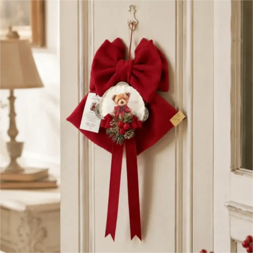 Fiocco rosso Dolce Teddy con medaglione orsetto, bacche rosse, rametti verdi e lunghi nastri pendenti.