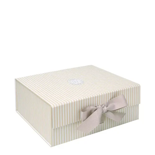 Boîte cadeau Mathilde M moyenne à rayures ivoire et blanches, avec couvercle, logo central et nœud frontal en gros-grain taupe.