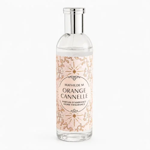 Parfum d’ambiance Mathilde M Orange Cannelle de 90 ml, en flacon de verre avec bouchon argenté et étiquette rose poudré décorée.