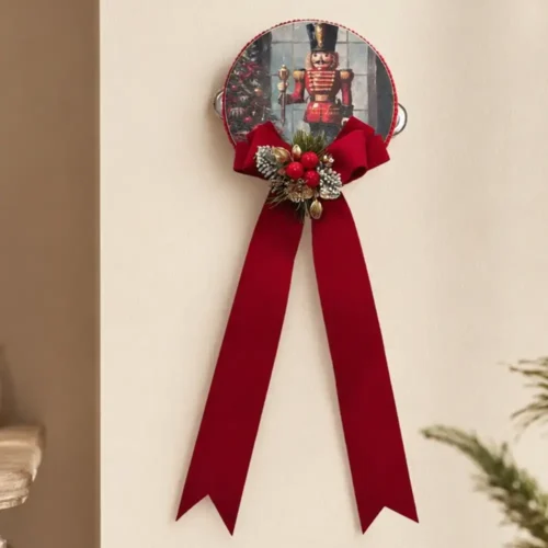 Pandereta navideña «Madame Fioccò» con cascanueces, un gran lazo rojo, bayas decorativas y detalles dorados.