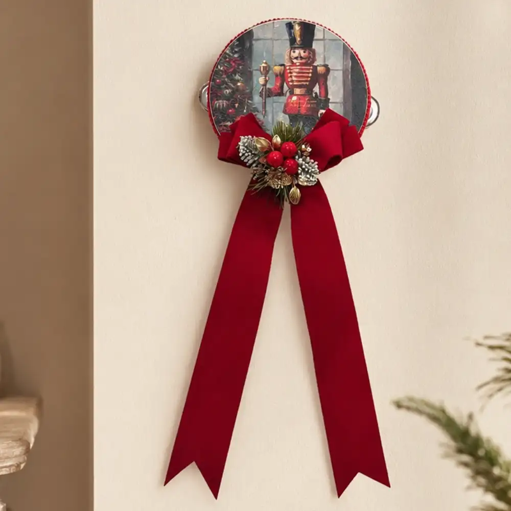 Pandereta navideña «Madame Fioccò» con cascanueces, un gran lazo rojo, bayas decorativas y detalles dorados.