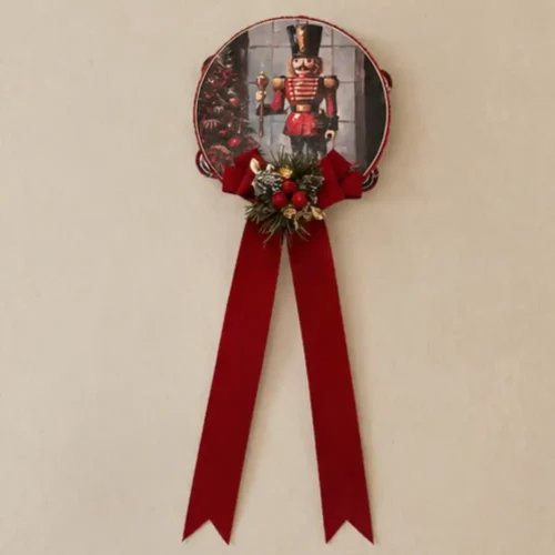 Pandereta «Madame Fioccò» con el Cascanueces, un gran lazo rojo y adornos navideños con bayas y ramitas.