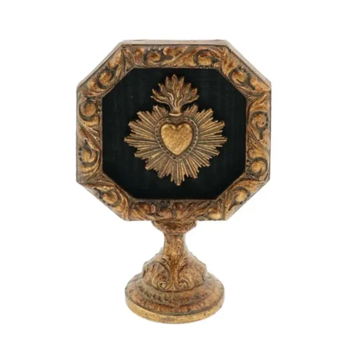 Decorazione Blanc Mariclò su piedistallo, con cornice dorata anticata, fondo nero e cuore votivo fiammeggiante in rilievo.