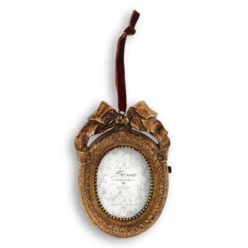 Portafoto ovale Blanc Mariclo Vivienne in resina dorata antichizzata, con fiocco decorativo e nastro bordeaux per appenderlo.